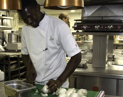 Chef slices an onion in the Galley. 