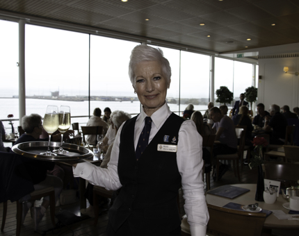 Waiter holds tray of drinks in the Royal Deck Tea Room. 
