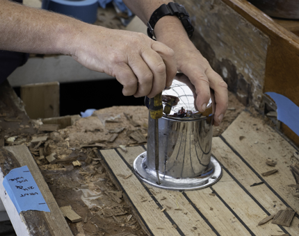 Man holds screwdriver and removes vent from deck.