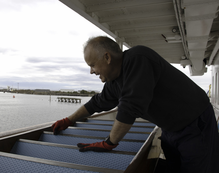 Maintenance team member cleans metal staircase treads. 