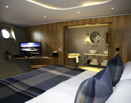 Inside a Fingal cabin with a bed and TV, with a view into the bathroom.