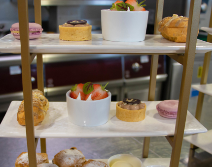 Tiered cake stand displaying a selection of colourful cakes, macarons and desserts. 