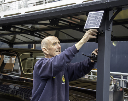 A man from the Facilities team fixing a solar panel to a post on the Rolls-Royce garage. 