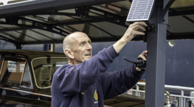 A man from the Facilities team fixing a solar panel to a post on the Rolls-Royce garage.  A man from the Facilities team fixing a solar panel to a post on the Rolls-Royce garage.