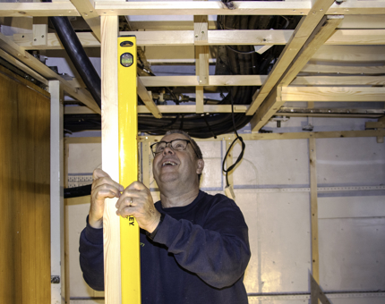 A man uses a spirit level to line up a wooden support in the new Training Room.