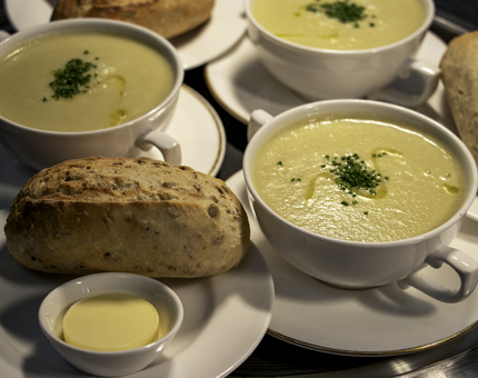 Bowls of Cullen Skink soup accompanied by a bread roll wait to be served. 