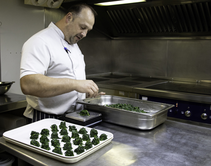 Chef prepares spinach in the Galley. 