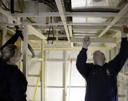 Maintenance team members finish off the deck framing in the ceiling of Britannia's Training Room. 