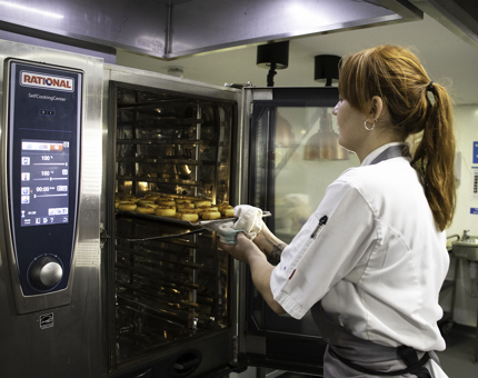 Chef removes a tray of pinwheel savouries from the Galley oven. 