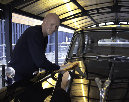Facilities officer polishes the Rolls Royce car. 