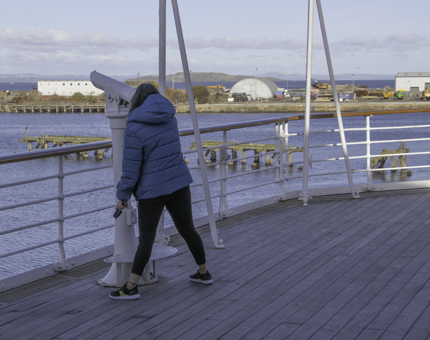 Visitor looks through the telescope on the Verandah Deck of Britannia. 