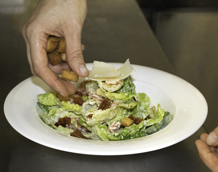 Chef adds finishing touches to a plate of salad. 