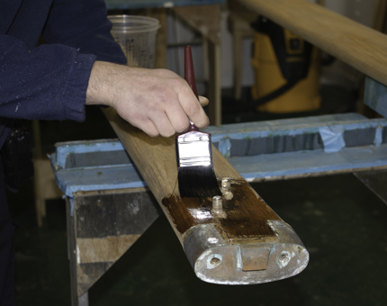 Close-up of maintenance man applying varnish to a wooden handrail.