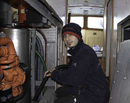 Maintenance team member holds a tube to clean from the bilges of the Royal Nore.