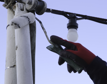 A close-up of a roller painting a pole with white paint.