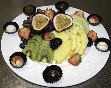 Close-up of fruit platter containing kiwi fruit, pineapple, passionfruit, strawberries, blackberries and chocolates.