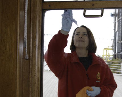 A Housekeeper cleaning windows in the Sun Lounge on board Britannia.