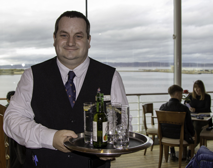 A Waiter holds a tray of drinks ready to serve to visitors in the Royal Deck Tearoom. 