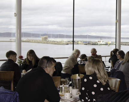 A busy Tearoom with many visitors sitting at tables enjoying tea and scones. 
