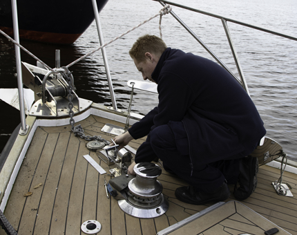 A man installs a new chain stopper on the boat, Royal Nore. 