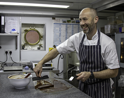 A Chef tempers chocolate in the Galley. 