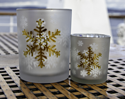 Two candleholders with snowflake designs. 