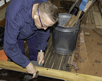 A member of the Maintenance team fits a cross traveller to a section of wood. 
