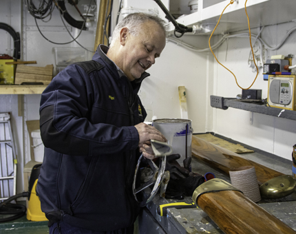 A man from Maintenance polishes the chrome on a speed control wheel. 