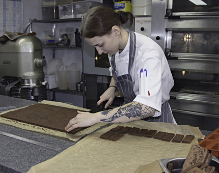 Chef cuts chocolate brownies into slices. 