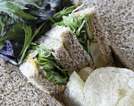 Close-up view of sandwich with a filling of courgette, hummus and rocket. 