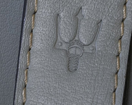 Close-up detail of a leather handle on wardrobe in a cabin showing the Fingal trident. 