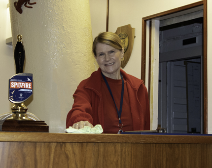 Woman Housekeeper wipes down the bar in the Unwinding Room at Britannia.