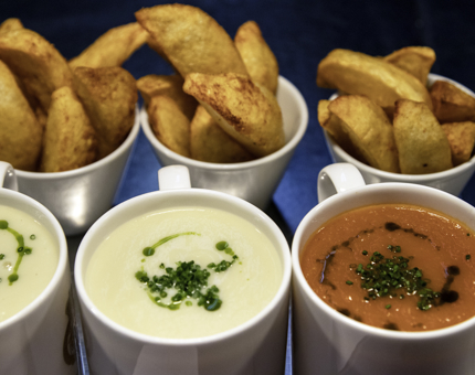Three mugs of soup with potato wedges.