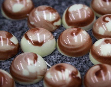 A close-up of a tray of round marble-effect topped chocolates. 