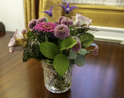 A vase of pink and purple flowers sits on a table. 