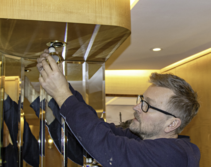 Maintenance team member replaces a lightbulb within a vanity unit in a cabin onboard Fingal. 