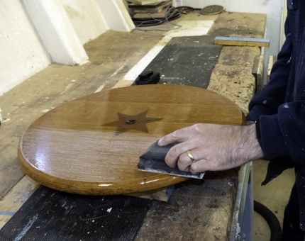 Maintenance man sands the round wooden top of the Rum Tub. 