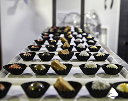 Many trays in a line containing mouthwatering brightly coloured artisan chocolates. 