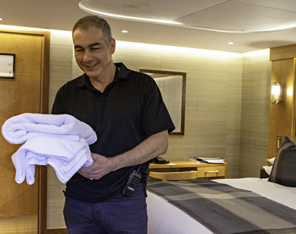 A member of the Housekeeping Team carries freshly laundered towels into a Fingal cabin.