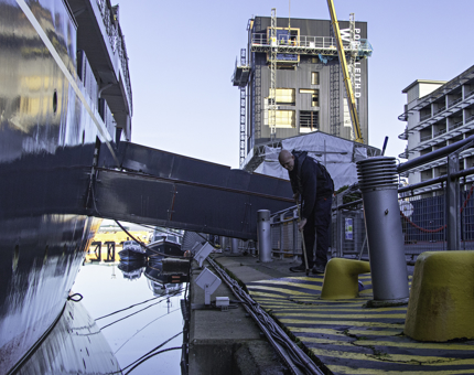 Maintenance team member weeds along the edge of the quayside, next to where Britannia is berthed.