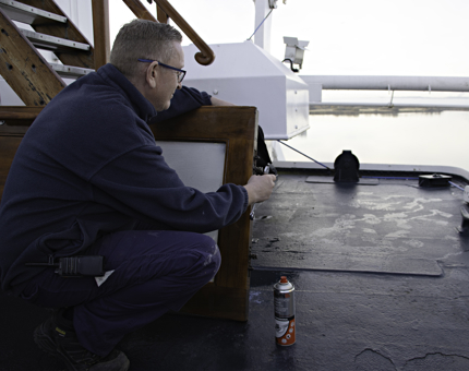 Maintenance team member holds a spanner to repair a wooden door that has been removed from its hinges. 