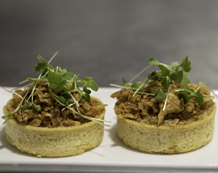Two mushroom tarts encased in pastry sit on a plate.