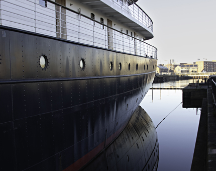 A side view of Fingal, on a crisp and bright winter's day. The sky is blue and the water is still.