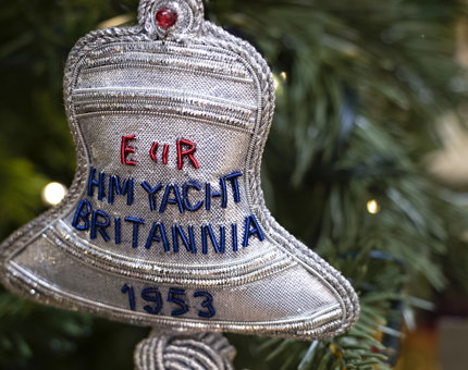 Silver embroidered Britannia Bell hanging decoration displayed on a Christmas tree. 