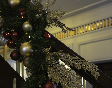 Close-up view of green foliage, gold and red baubles and gold glittery foliage on the Grand Staircase.