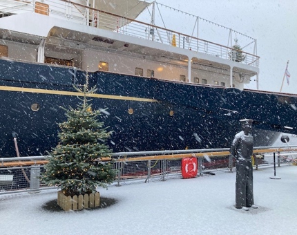 Snow on the ground with a Christmas tree next to Britannia. 