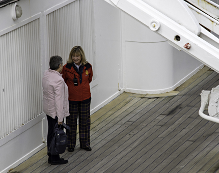 A Visitor Assistant stands talking to a woman visitor on an outside deck. 