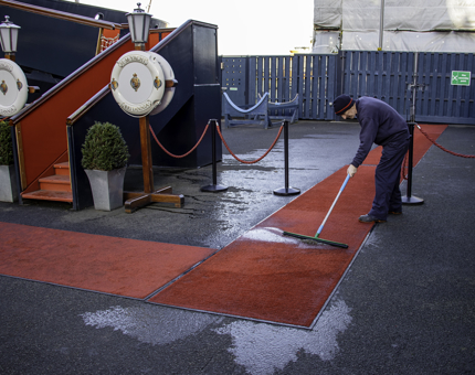 Britannia staff member cleans the red carpet outside the Royal Brow.