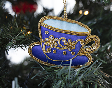 Close-up of an embroidered tea cup-shaped decoration hanging on a Christmas tree. 