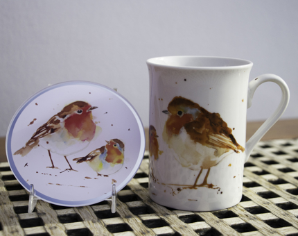 An illustrated drinks coaster and mug depicting robins. 